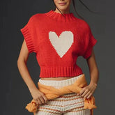 Person wearing a red knitted top with a heart design on a dark background